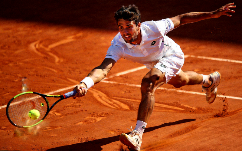 网球运动员在红土场上奋力击球的动态照片